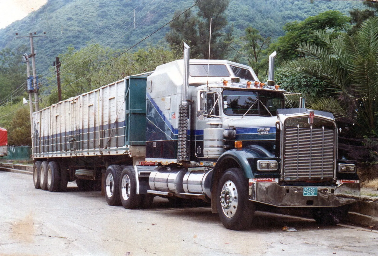 Primer tractocamión Kenworth de la empresa con caja de carga, estacionado junto a la sierra